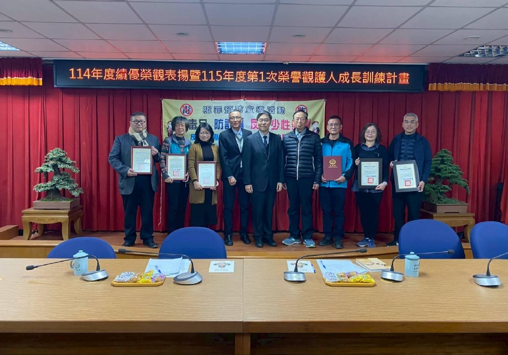 Two chief prosecutors pose for a photo with award-winning teacher Rong Guan.